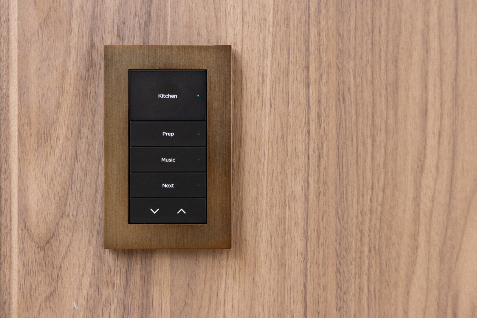 An engraved Control4 keypad in an aged brass finish on walnut paneling