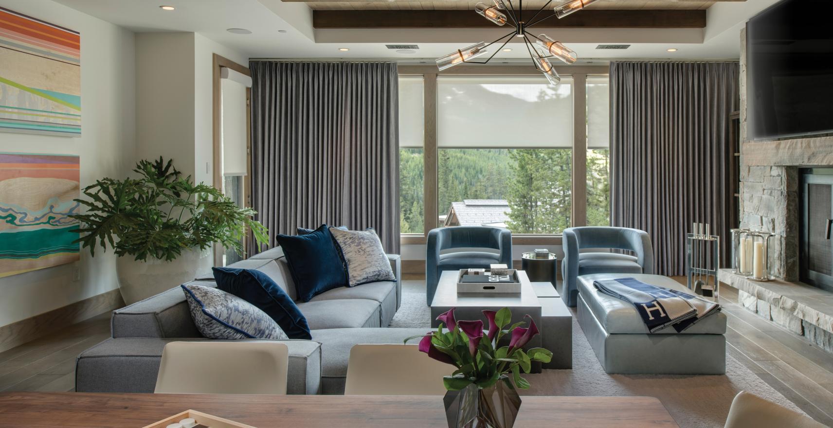 Motorized drapery and roller shades across a living room window wall
