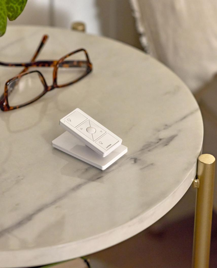 Pico remote on a white pedestal beside glasses on a marble table