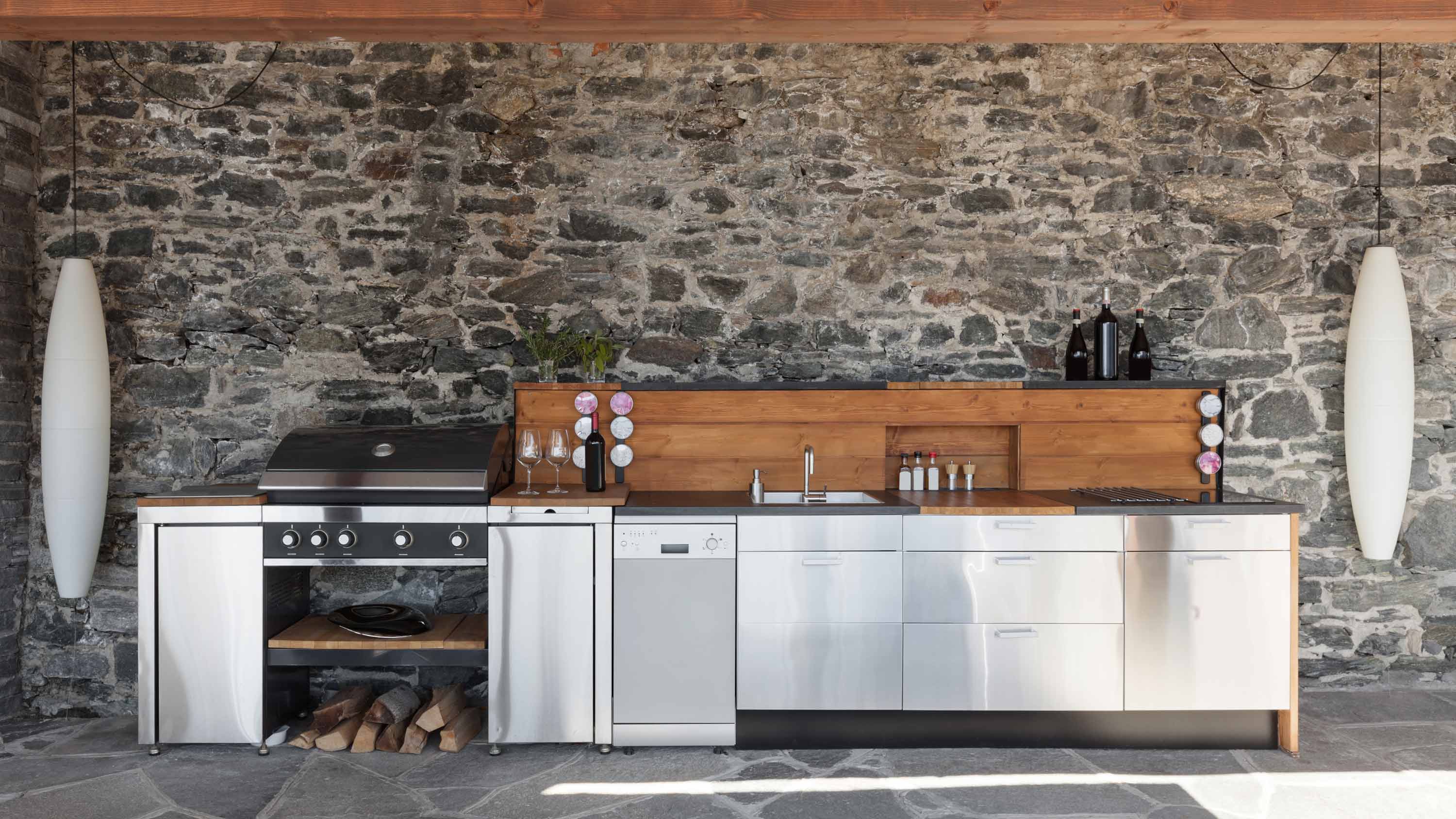 Outdoor kitchen with a grill, task lighting, and speakers for entertaining