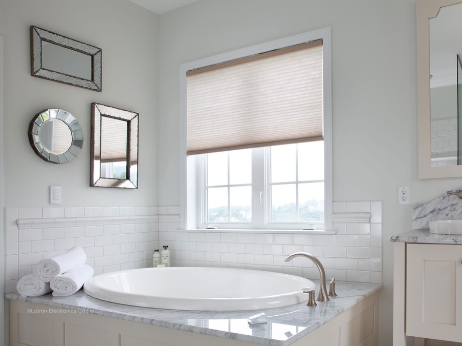 Lutron wireless shades installed on a bathroom window next to a bathtub