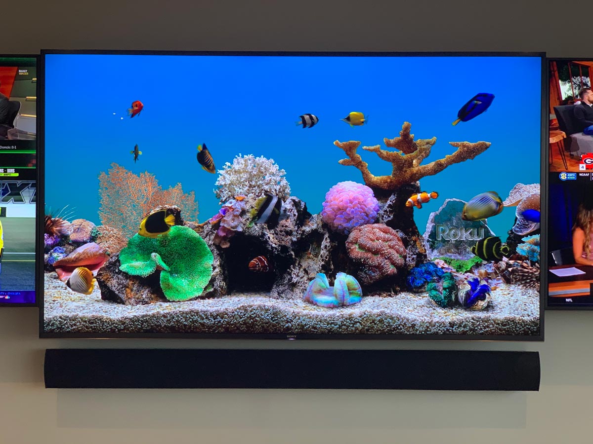 Wall TV and soundbar flanked by side screens