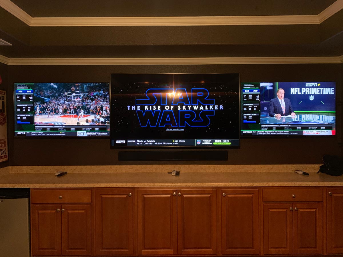 Triple-screen media wall above built-in cabinets