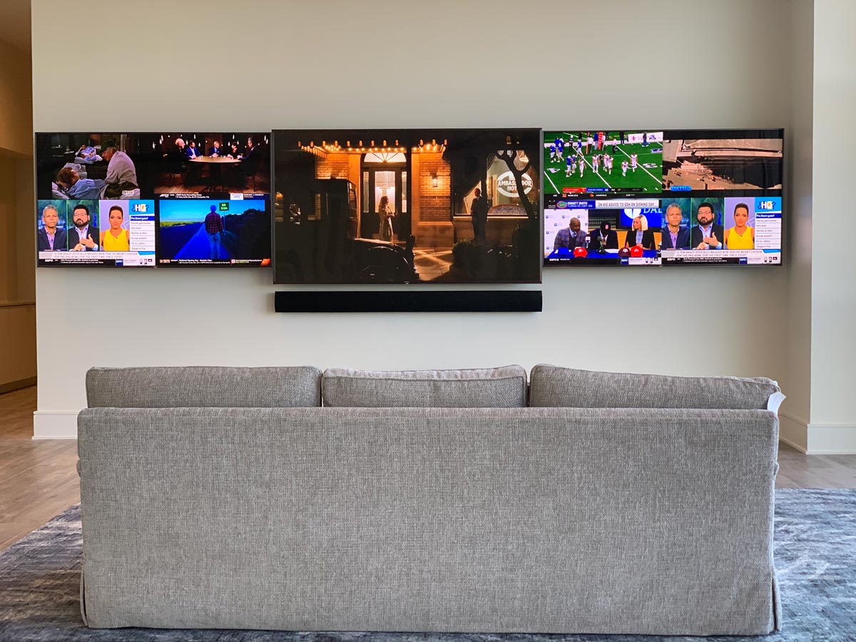 Three TVs and a soundbar on the living room wall