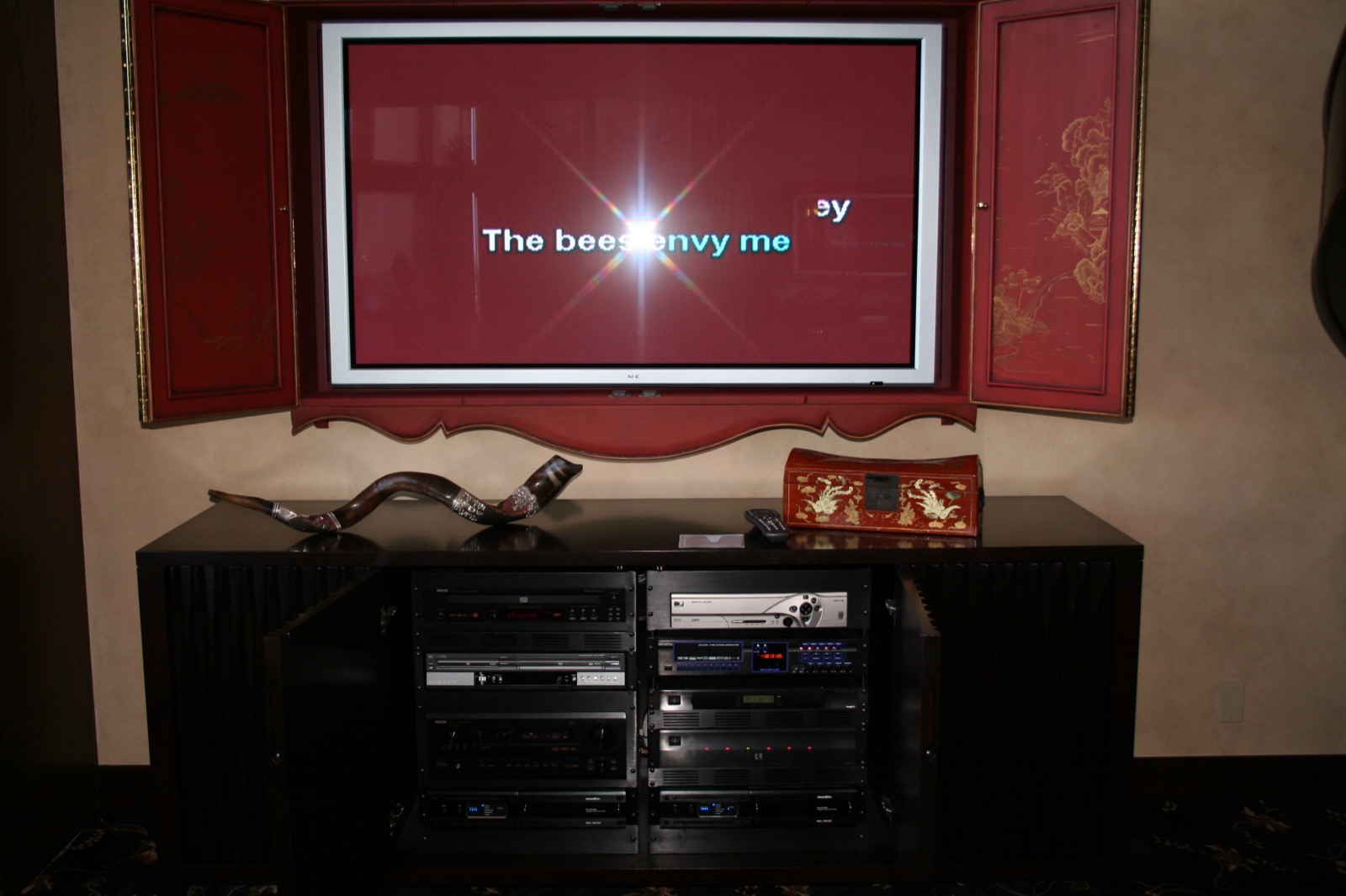 Plasma TV revealed behind painted cabinet doors with the equipment rack concealed below