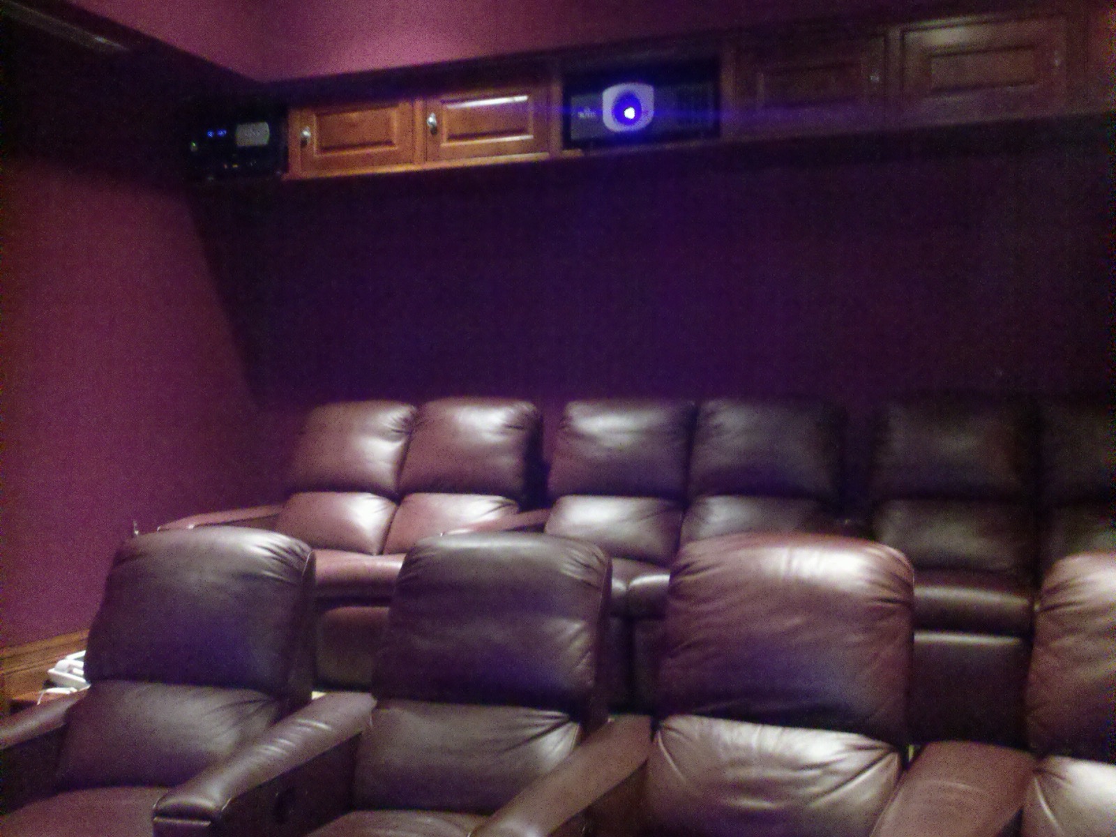 Rows of leather recliners in a Lake Austin home theater with a rear projector cabinet