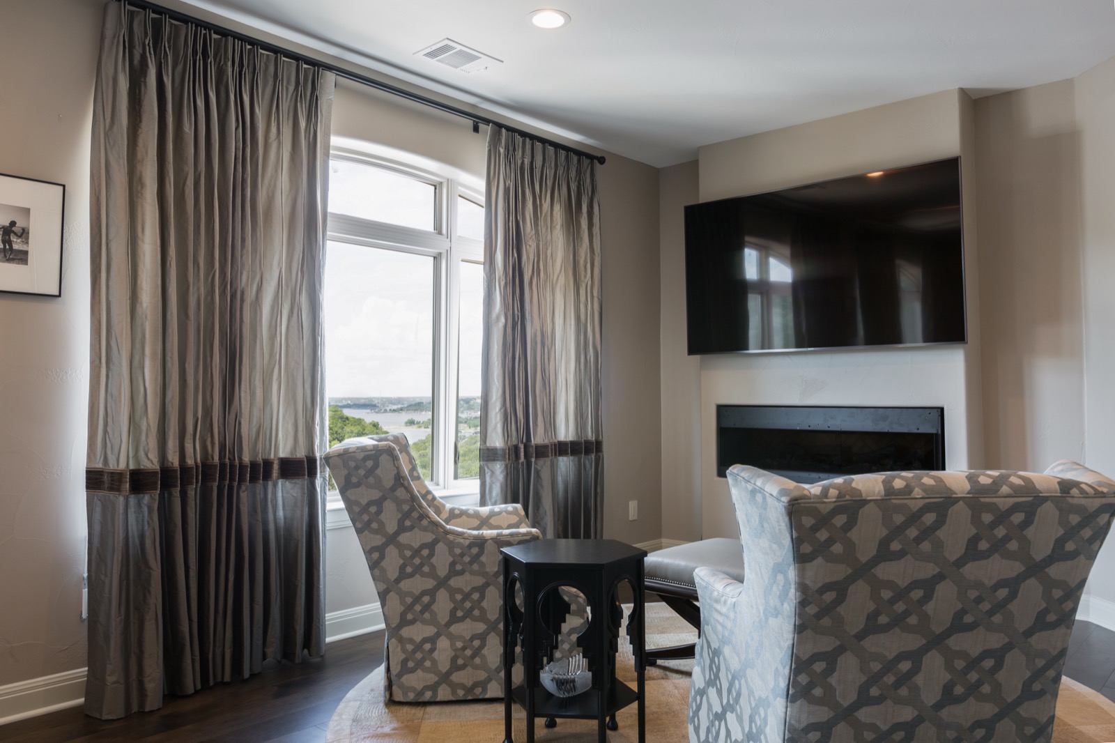 Master sitting area with a TV above the linear fireplace and a lake view