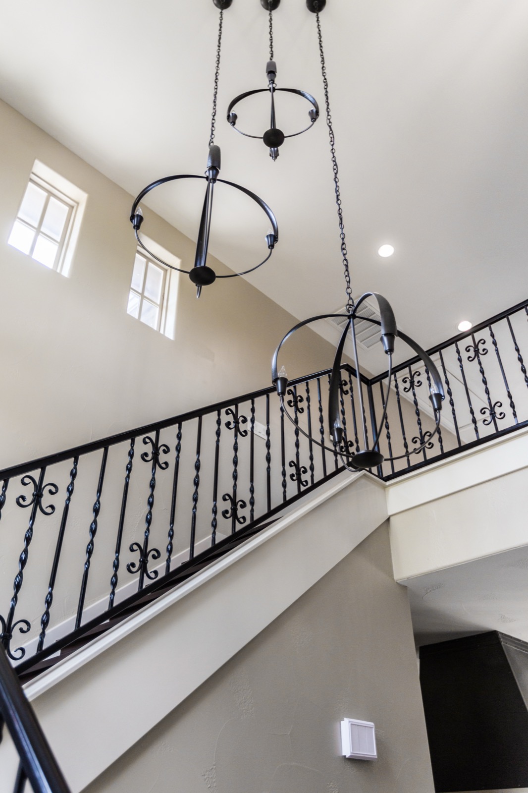 Stairwell chandeliers over a wrought iron railing