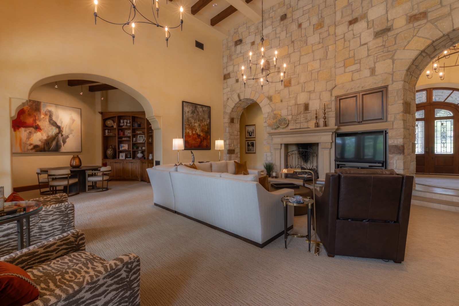 Great room with a TV beside the stone fireplace under a vaulted ceiling
