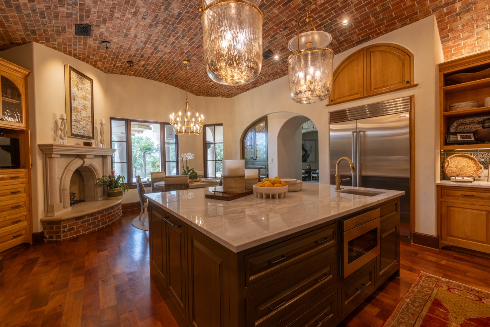 Kitchen island under pendant lights and a brick barrel ceiling