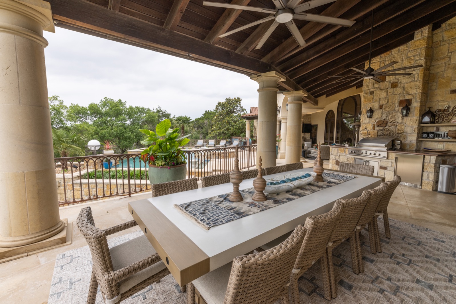 Covered outdoor kitchen and dining terrace overlooking the pool