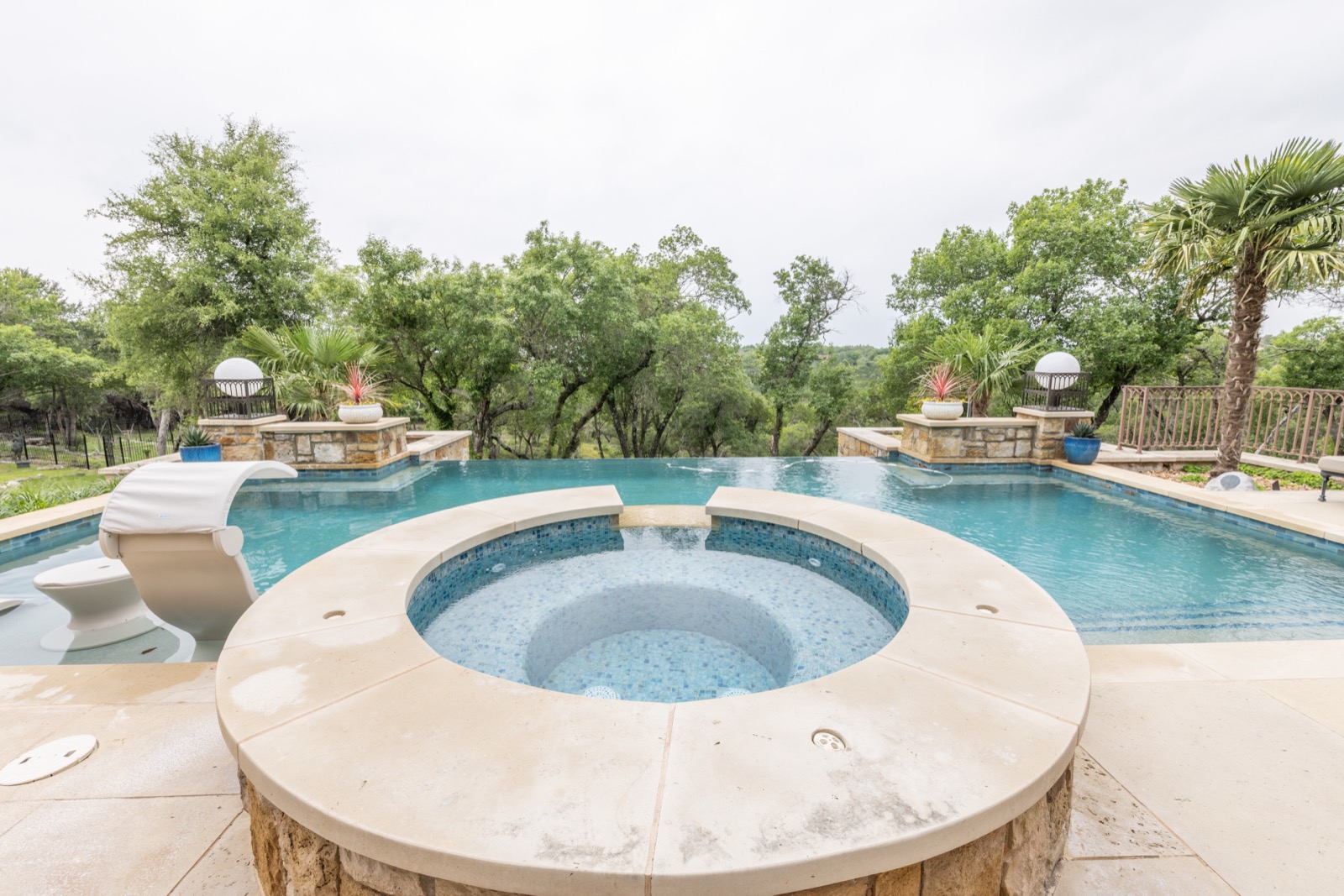 Pool and raised spa with hill country trees beyond