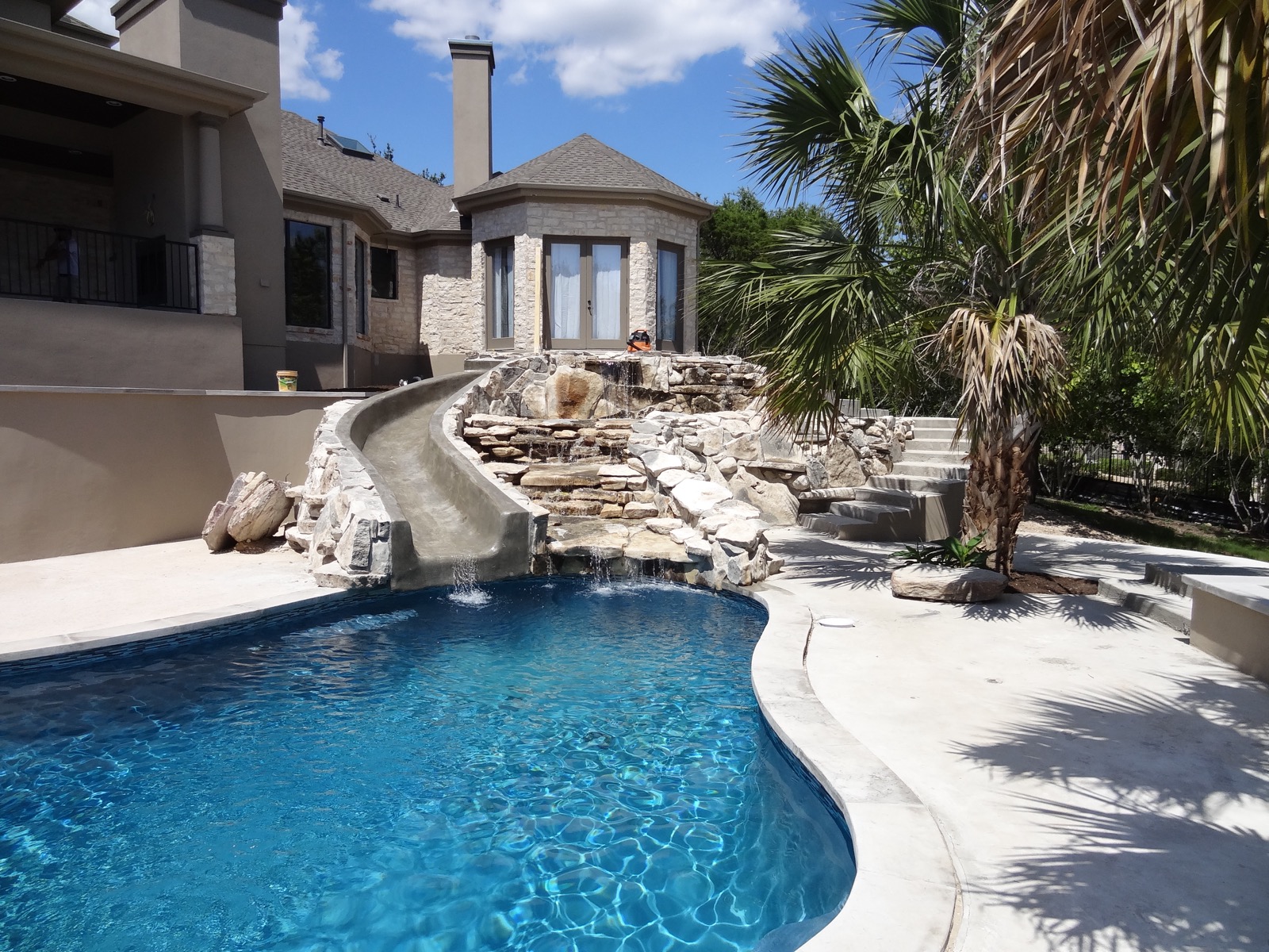 Backyard pool with a stone waterfall and slide at a Riverplace remodel