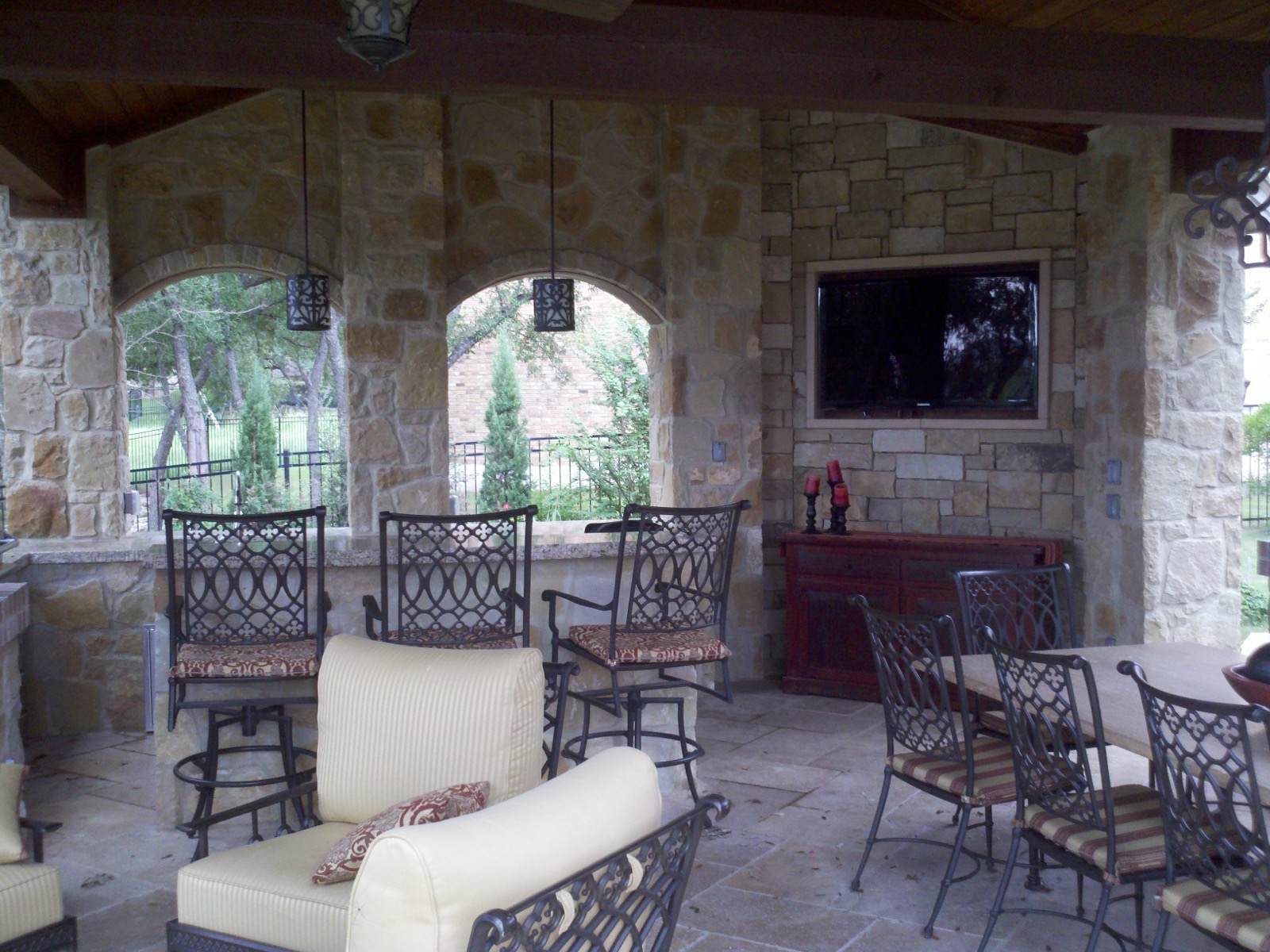 Covered outdoor living area in Steiner Ranch with a TV set into the stone wall