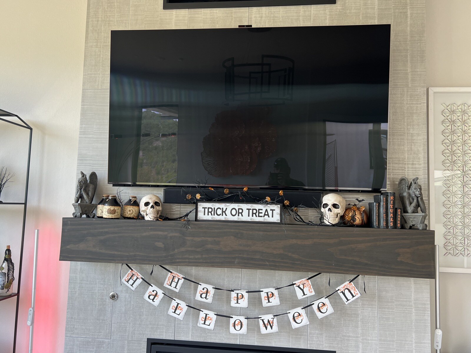 TV mounted above a wood mantel and stone fireplace with a Halloween banner