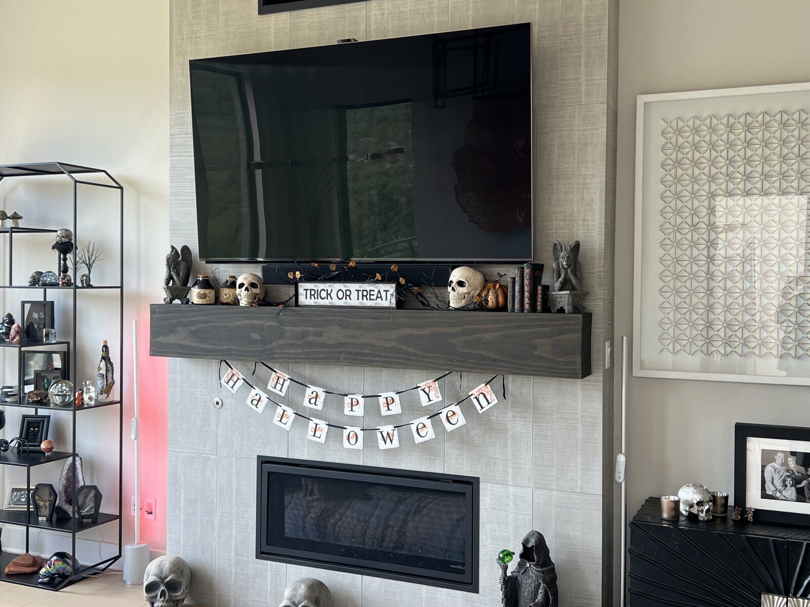 Angled view of a TV above a stone fireplace, with Halloween decorations across the wood mantel