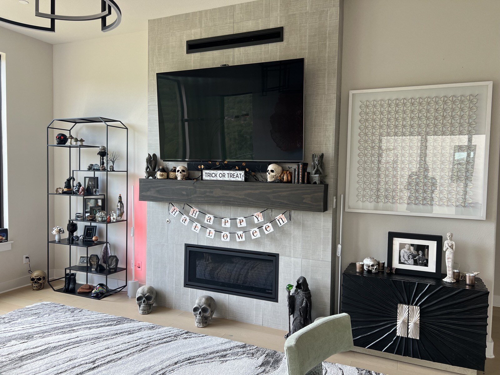 TV above a stone fireplace and wood mantel, with a display shelf and a cabinet beside it