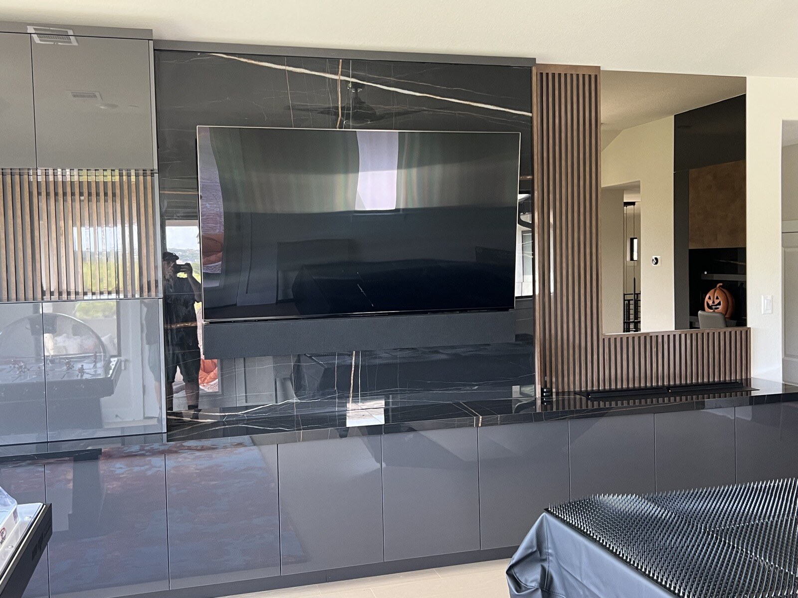 Front view of a TV and soundbar mounted on dark stone above a long run of cabinets