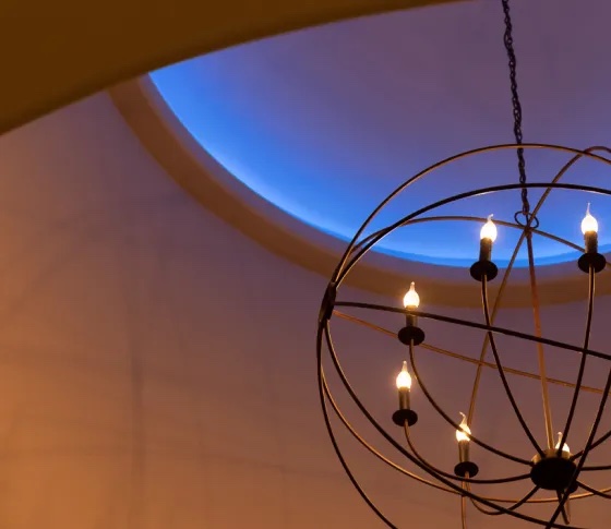 A chandelier under a ceiling cove glowing blue from Vibrant color-changing LEDs