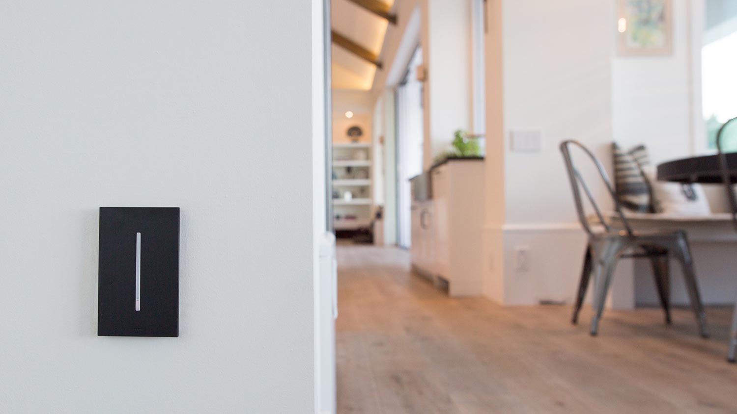 Black Lutron HomeWorks keypad mounted on a wall near an open living space