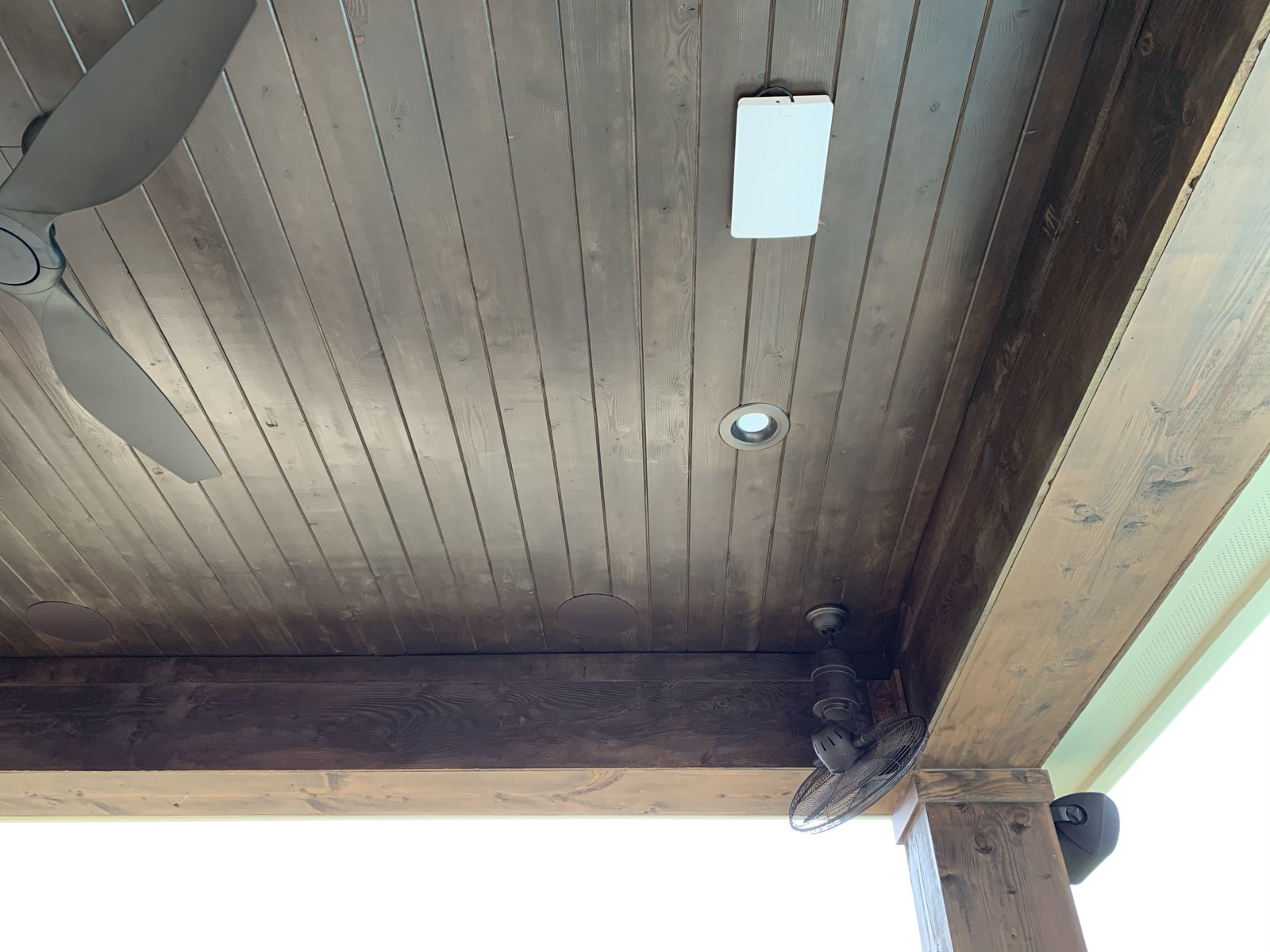 Wireless access point mounted on a wood patio ceiling beside a fan and in-ceiling speaker