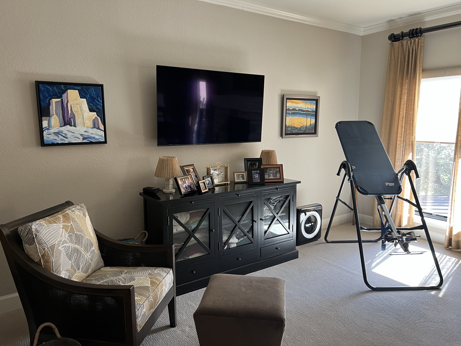 A wall-mounted TV above the media cabinet in the bedroom sitting area
