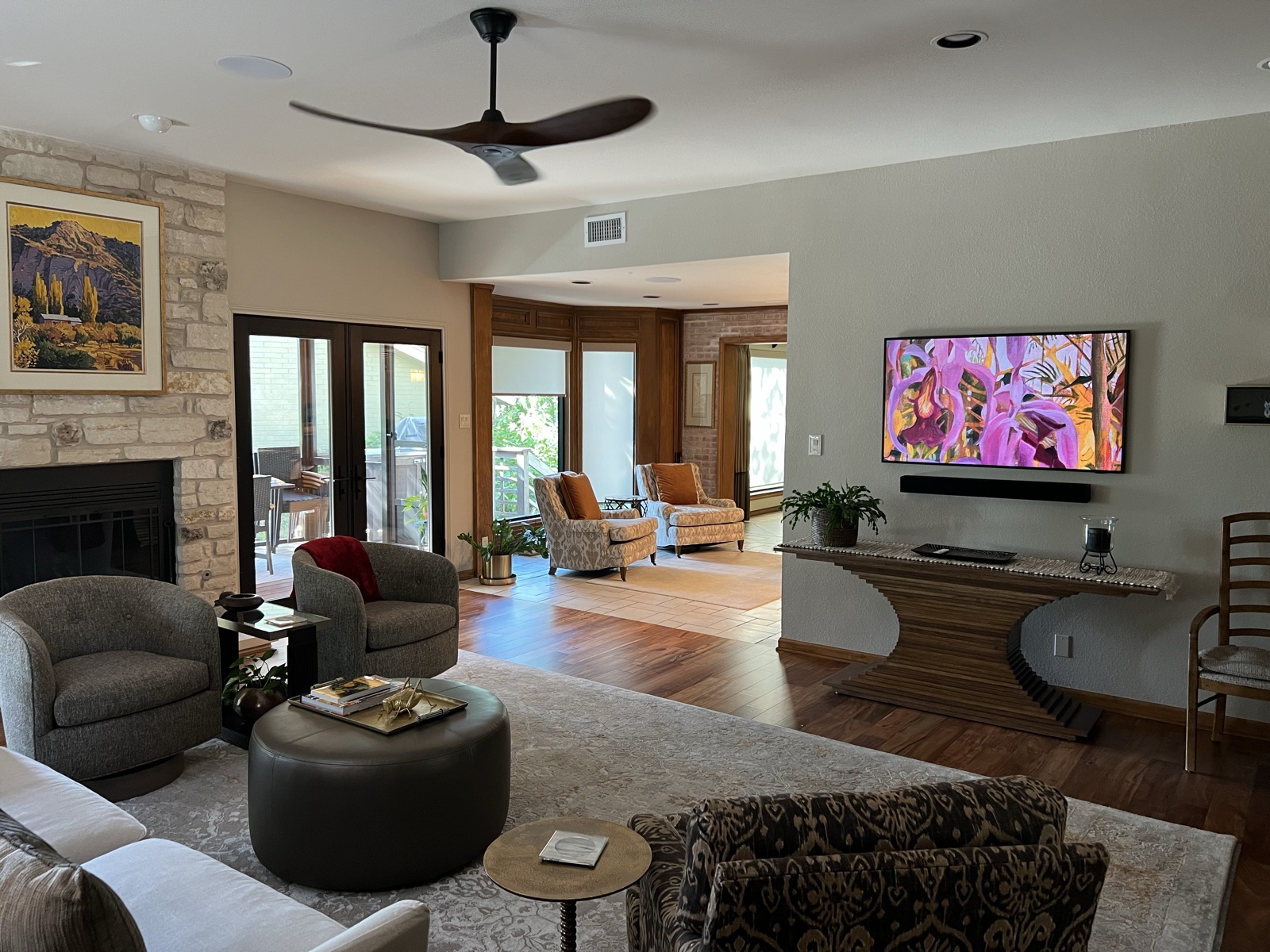 The great room at the Austin home remodel: stone fireplace, in-ceiling speakers, and a Frame display showing art above a console table