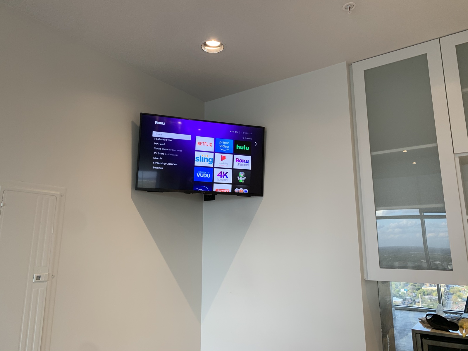 The bar TV, corner-mounted between the cabinets and the window