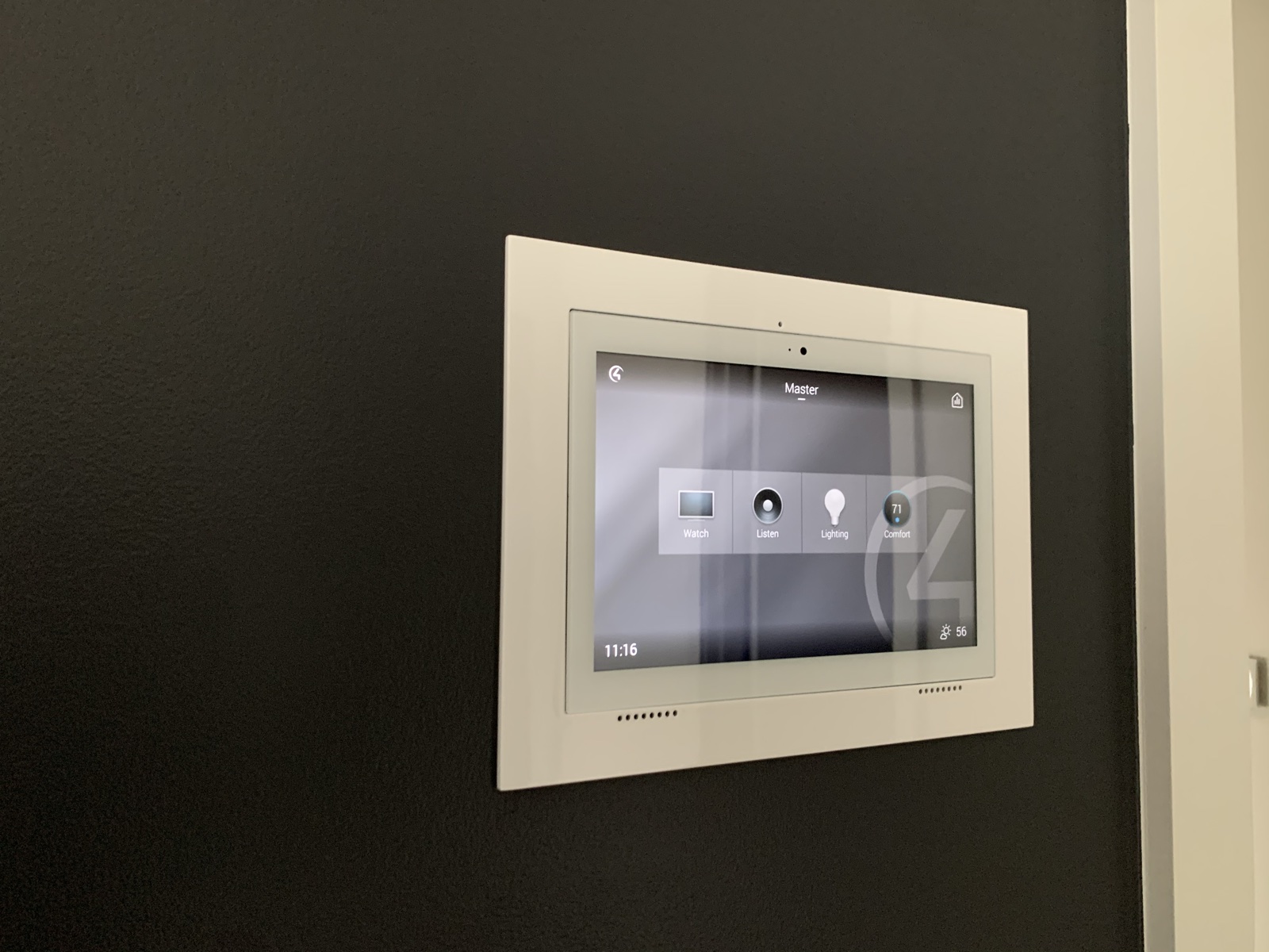 A Control4 touch screen flush-mounted in a dark accent wall