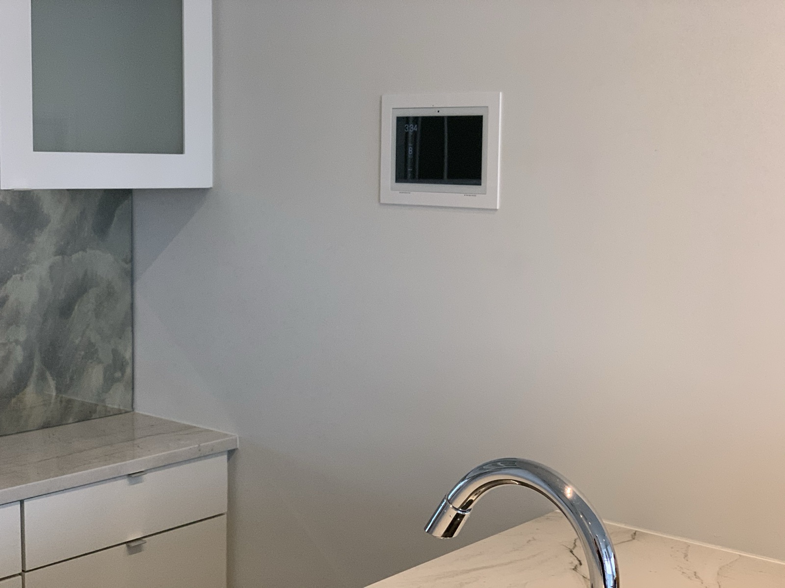A compact touch screen flush-mounted in the kitchen wall beside the island