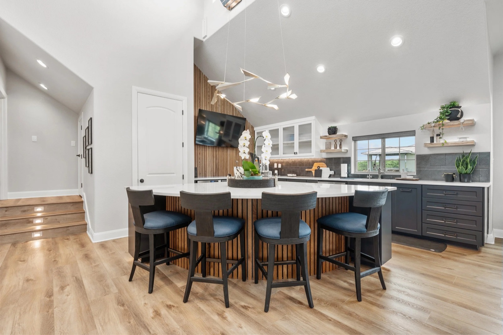 The lounge kitchen at the Kingsland residence with a wall-mounted TV on the wood-slat accent wall and a large island