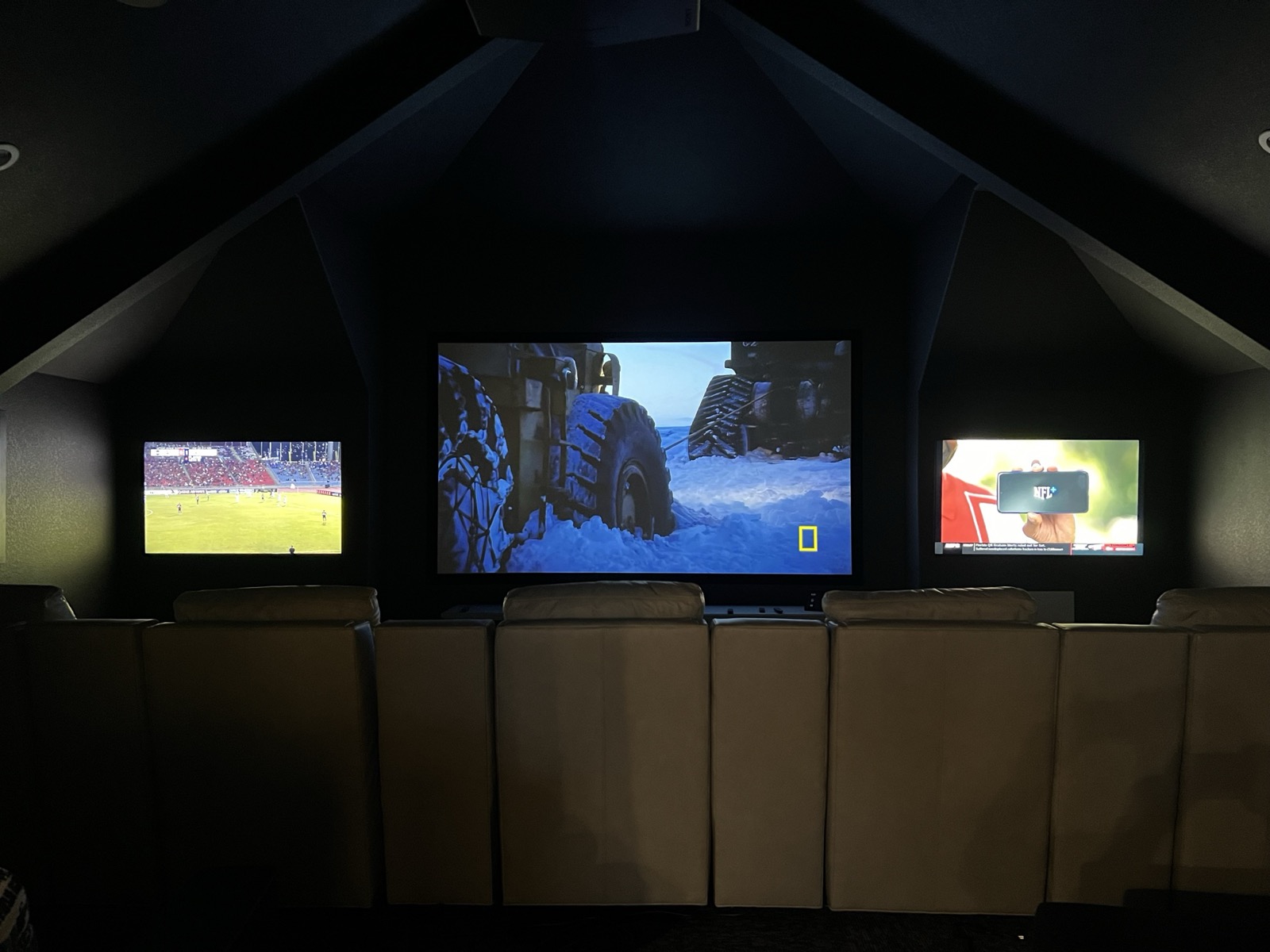 The Kingsland home theater in use on game day, the main screen flanked by two displays each showing a different game, seen from the tiered seating