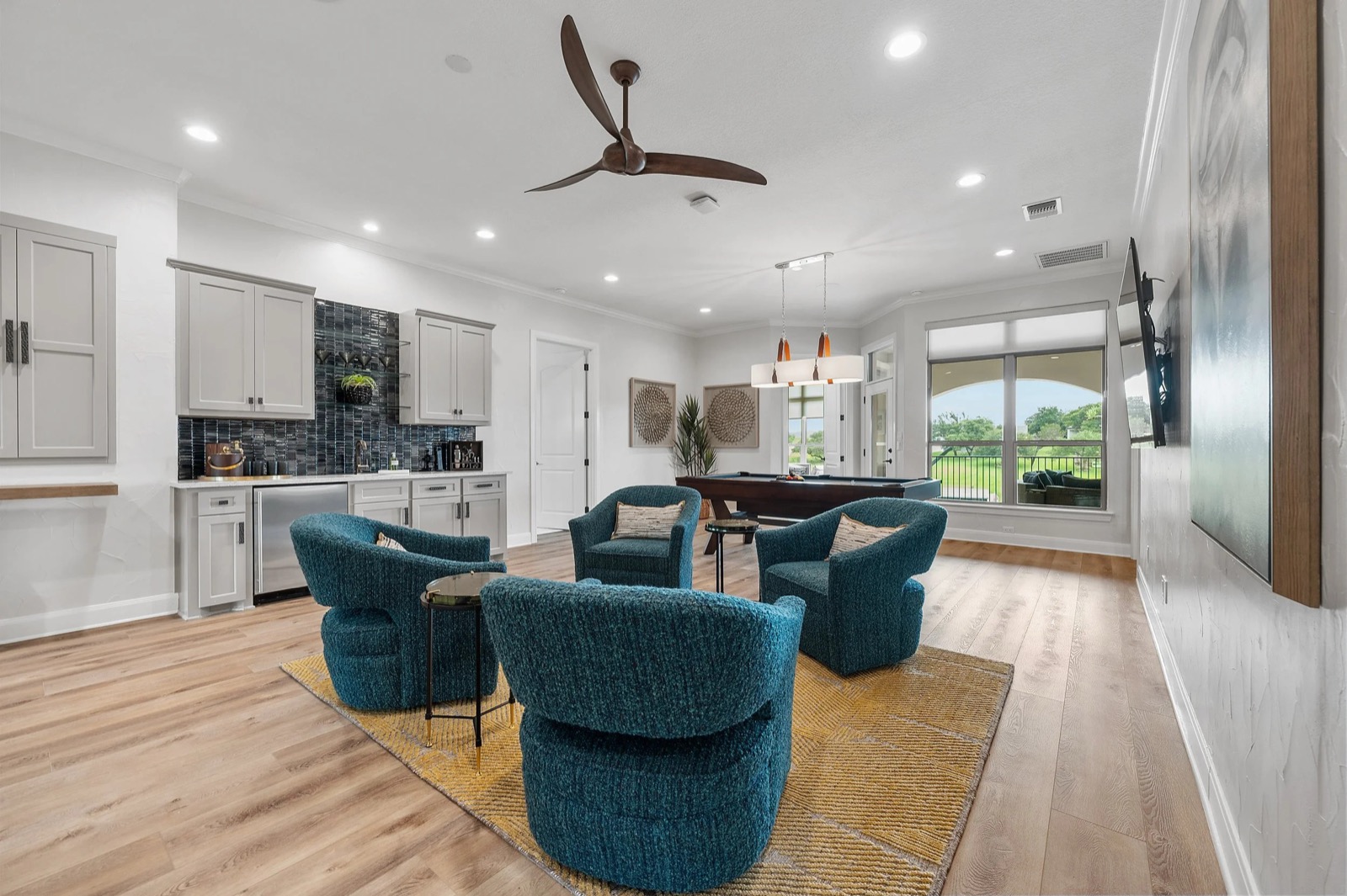 Another view of the upstairs loft at the Kingsland residence, with a wet bar, a pool table, and a wall-mounted TV, and the hill country beyond