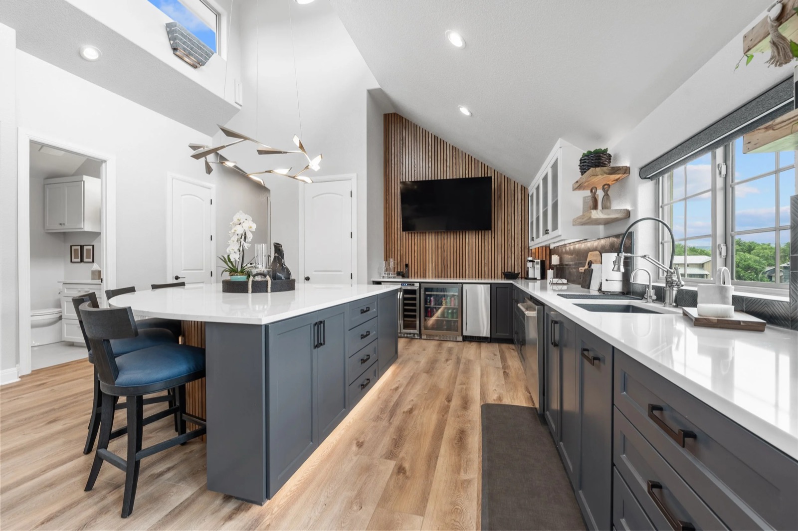 Upstairs lounge at the Kingsland residence, seen long, with a TV mounted on the wood slat wall past the kitchenette