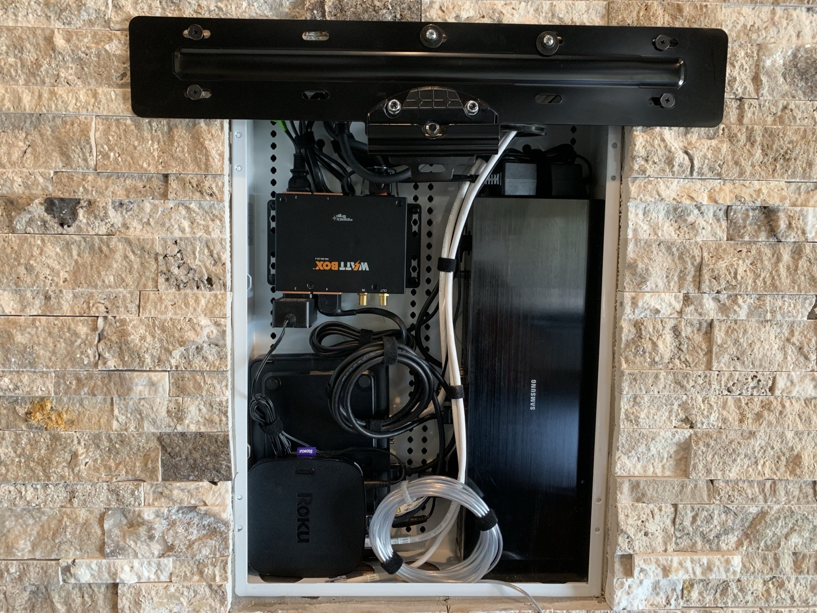 Concealed AV equipment, including a WattBox and streaming gear, behind a display at the Lake Travis estate