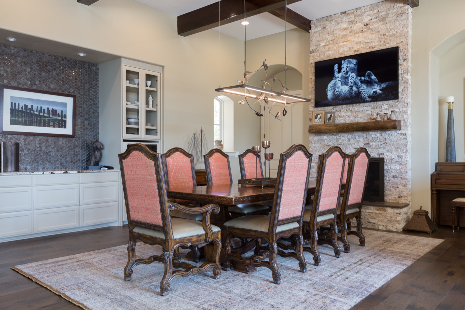 The formal dining room at the Lake Travis estate with a wall-mounted TV and an iron chandelier
