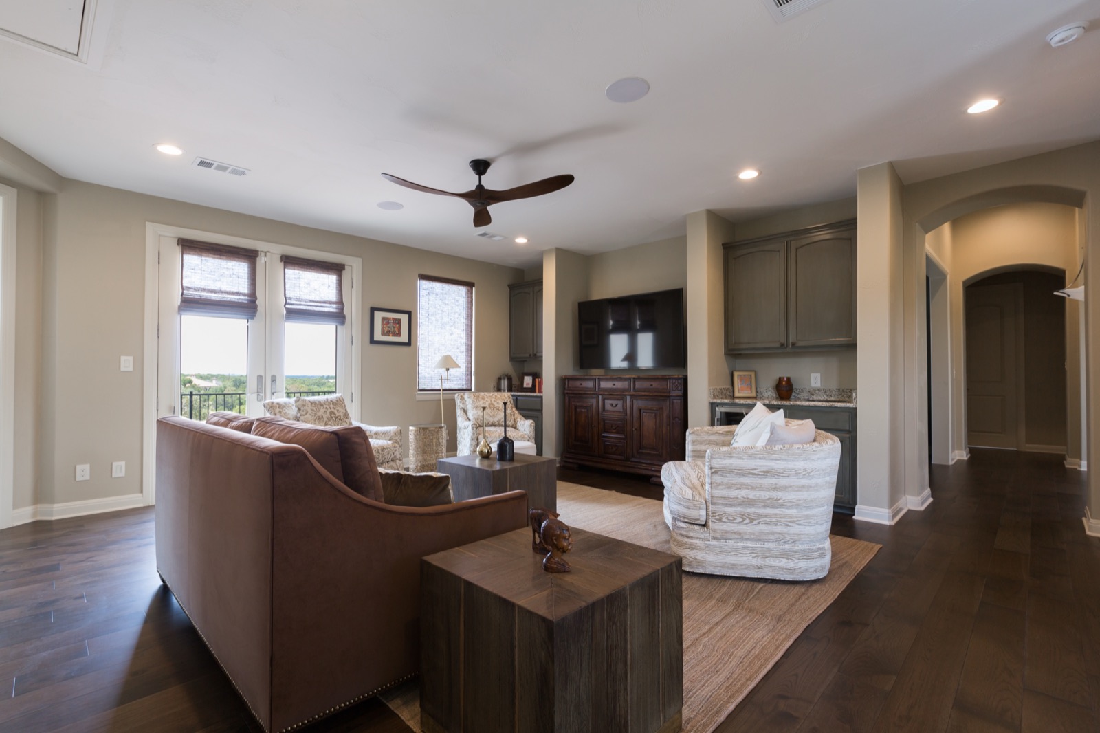 The living room at the Lake Travis estate with a sectional and concealed whole-home audio, open to the kitchen
