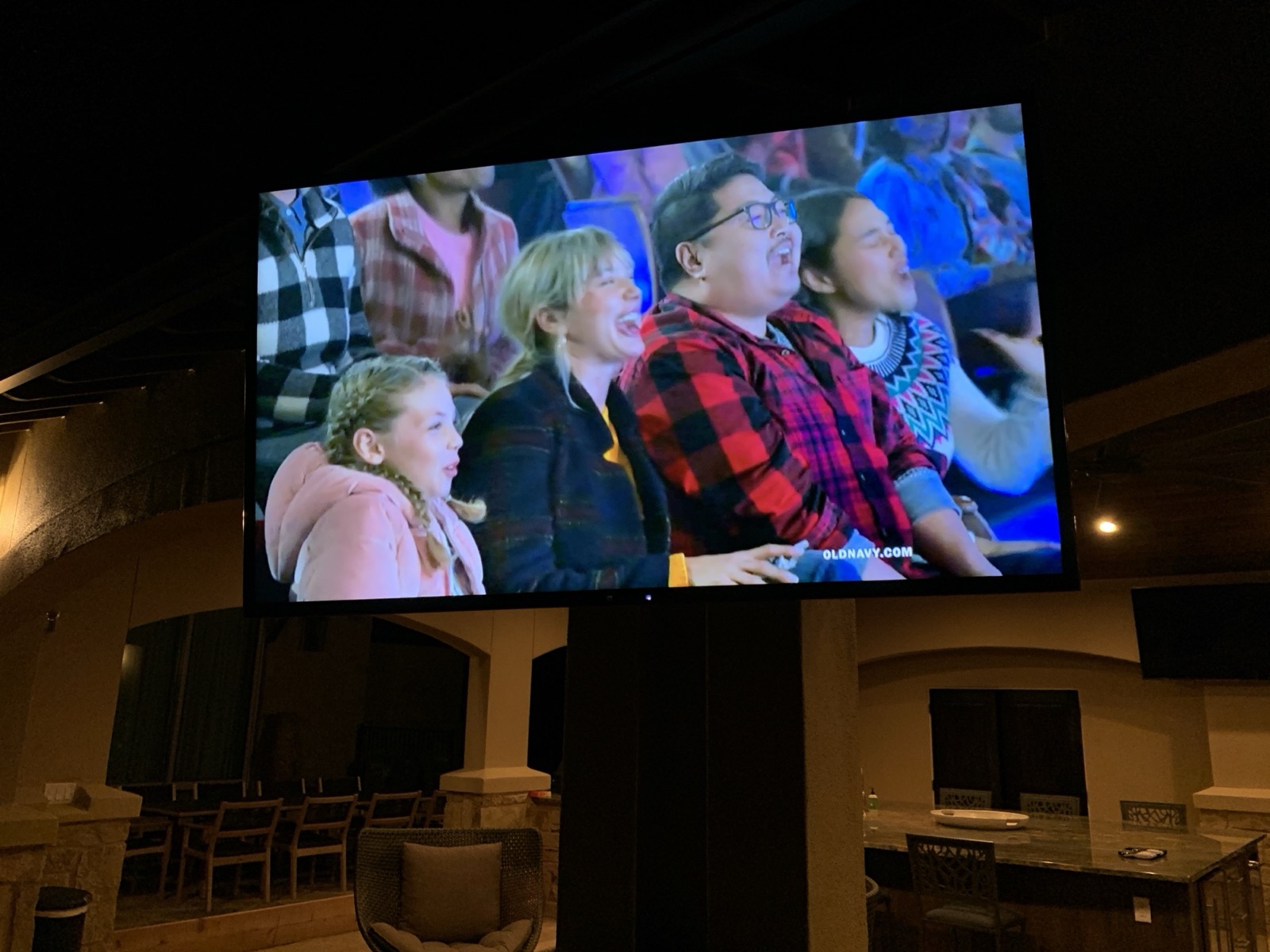The covered patio TV lit at night at the Lake Travis estate