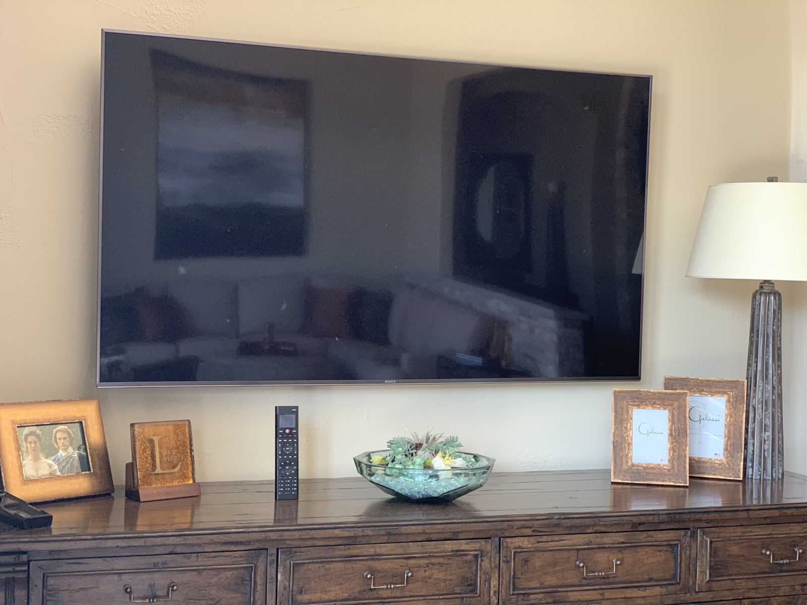 The sitting room at the Lake Travis estate with a wall-mounted TV and a Control4 remote on the console