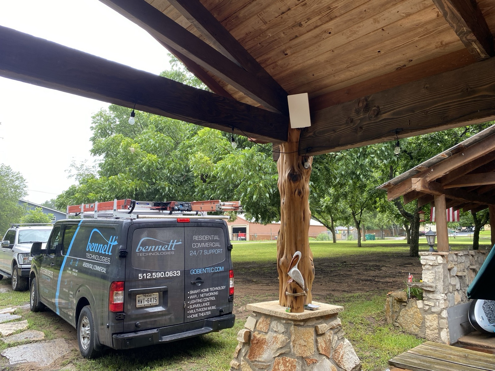 The Bennett Technologies work van parked beside a covered stone patio in Marble Falls, with an outdoor speaker mounted under the wood-beam ceiling
