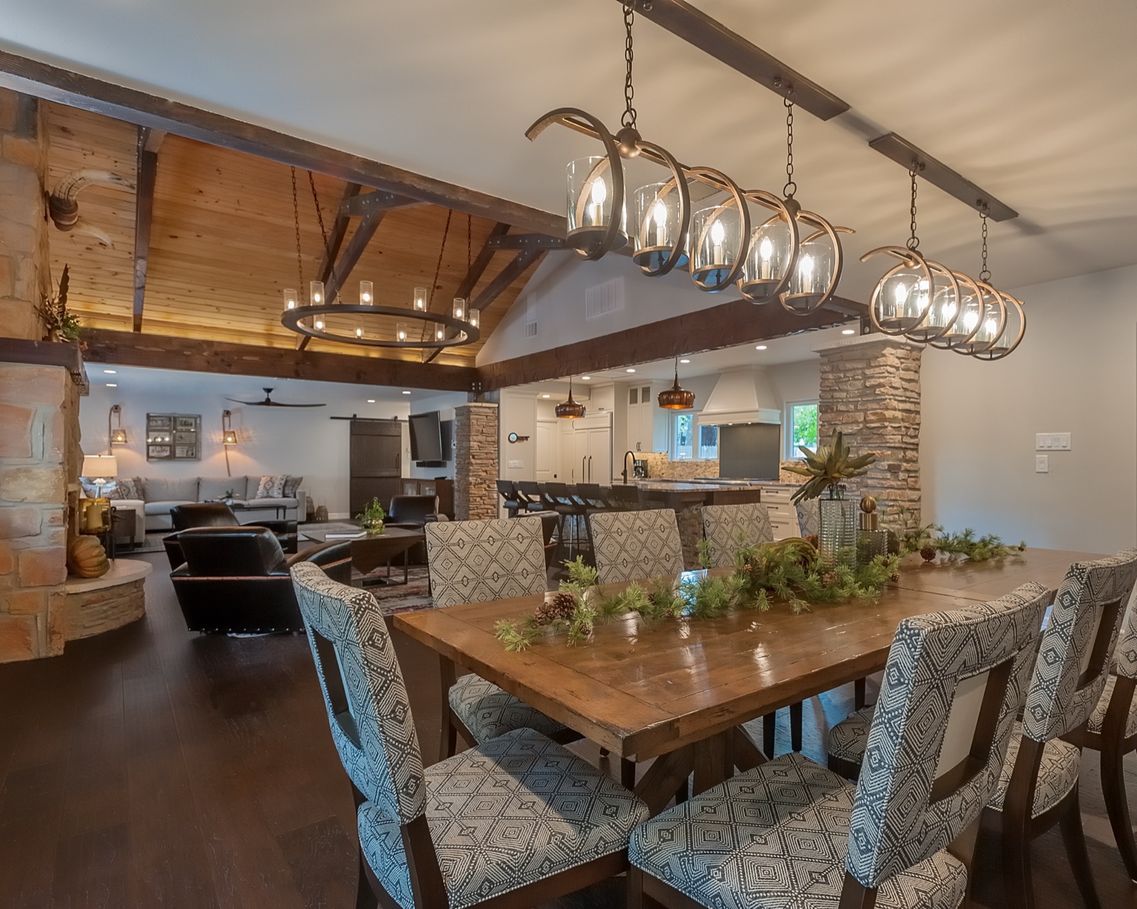 Dining table under iron ring chandeliers at the Marble Falls retreat, open to the kitchen and great room