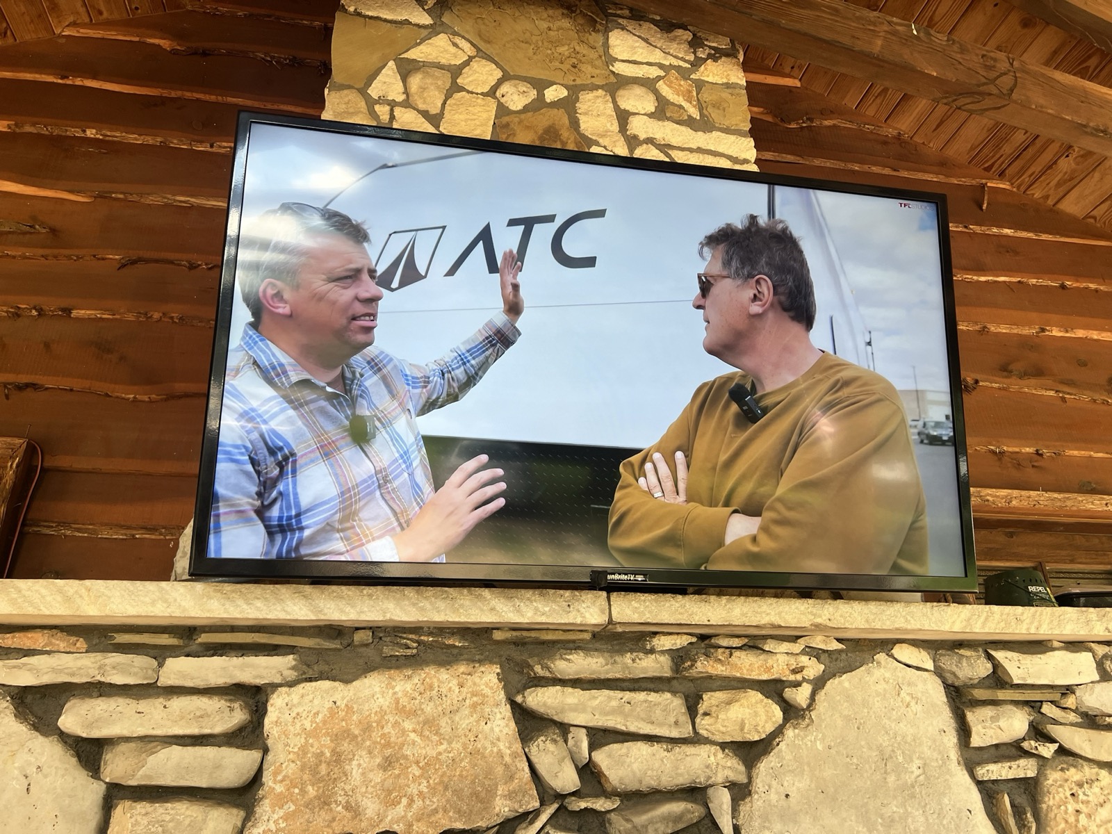 Outdoor TV mounted on the stone chimney of the covered front patio at the Marble Falls retreat