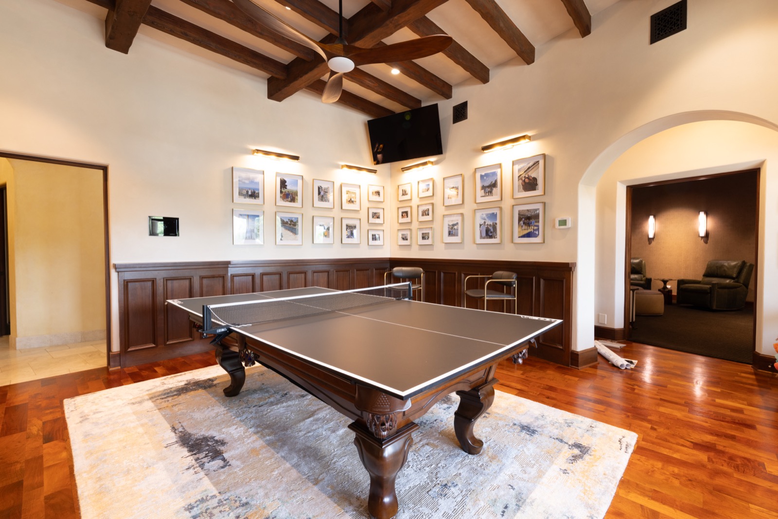 The game room at the Northwest Austin home with a game table, a wall of framed photos, and a wall-mounted TV