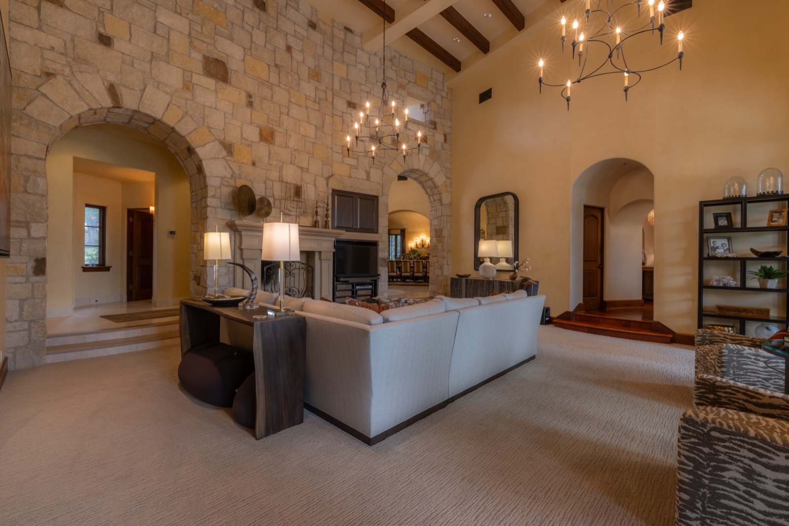 The great room at the Northwest Austin home under a vaulted ceiling, with a stone fireplace and whole-home audio