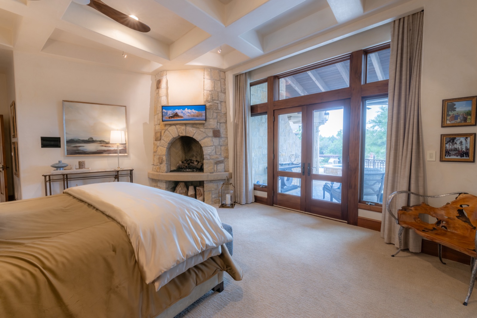 The master bedroom at the Northwest Austin home with an in-wall Control4 touch screen and a display above the stone fireplace