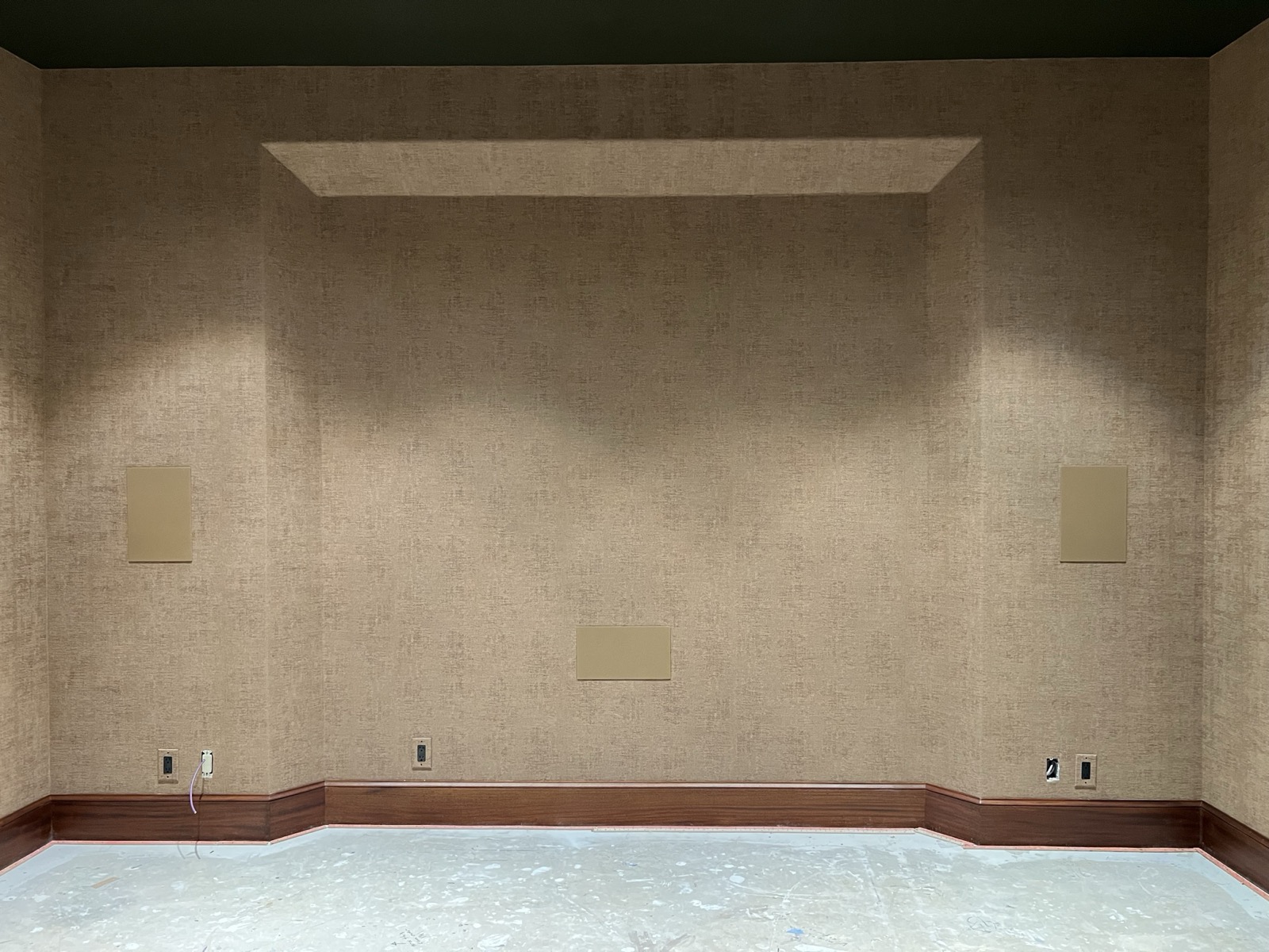 The media room's acoustic fabric wall and screen recess at the Northwest Austin home, with in-wall speaker panels, during the build
