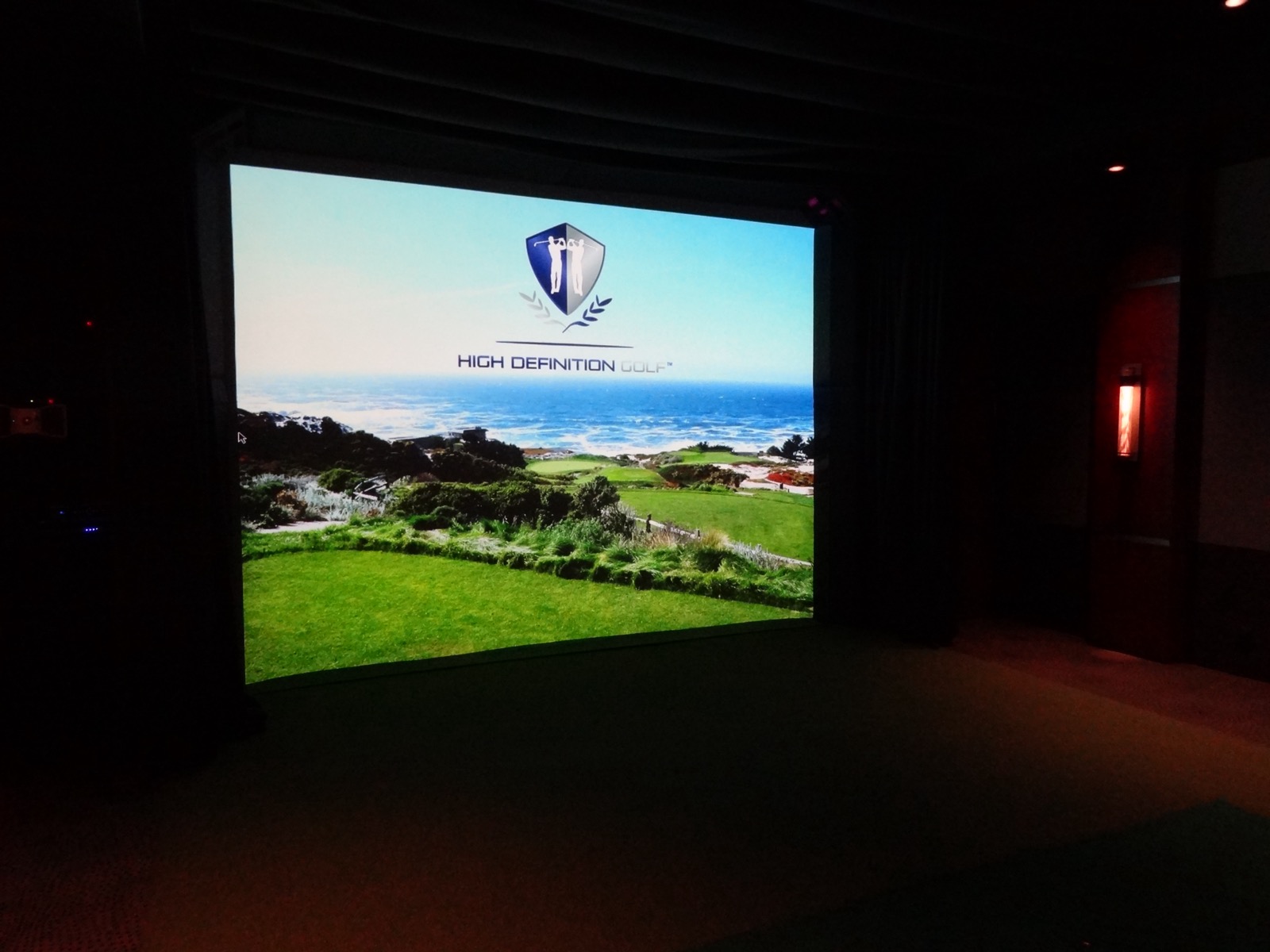 The golf simulator screen at the Tarrytown pavilion showing the High Definition Golf course view, with turf underfoot