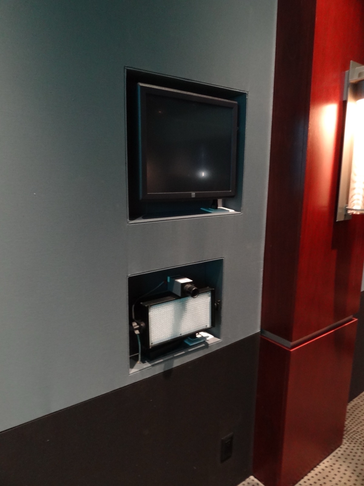 Control panel and swing analytics screen inset into the media room side wall below a recessed display