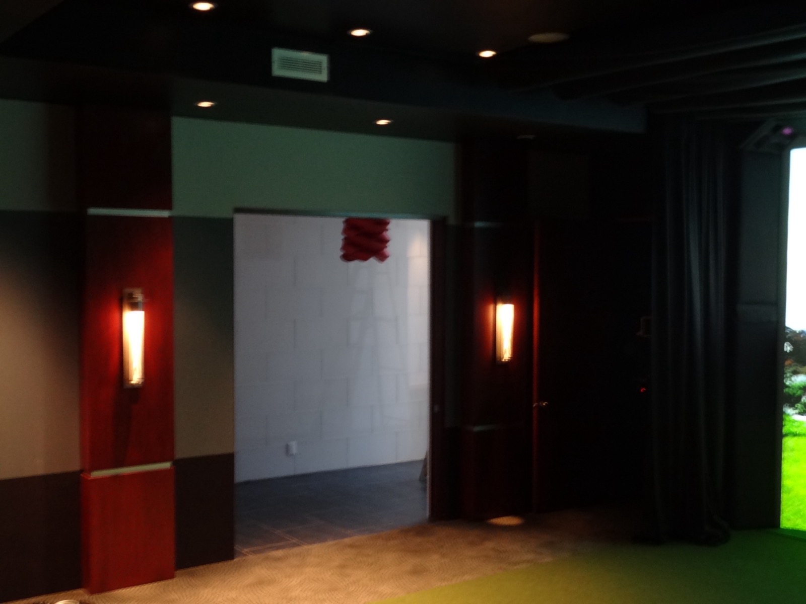 Entry into the Tarrytown media room, with sconces in the mahogany pilasters and the simulator curtain at right