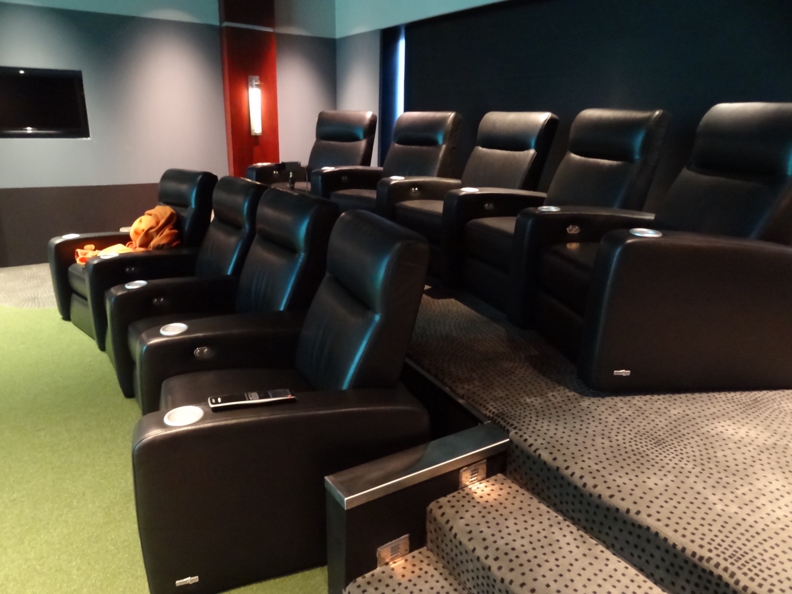Theater risers lit by step lights, with the turf hitting area at left and a display set flush into the side wall